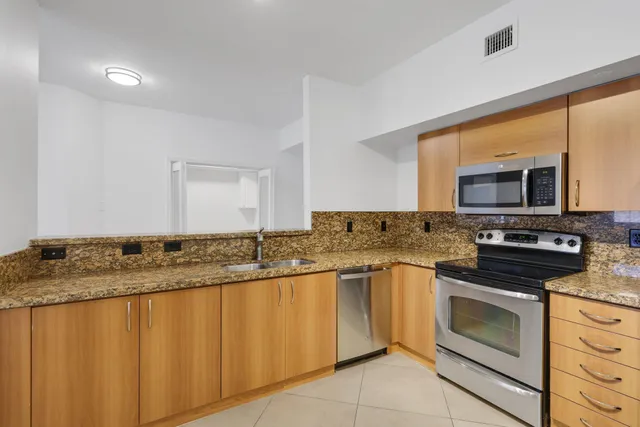 a kitchen with granite countertop stainless steel appliances a stove sink and microwave