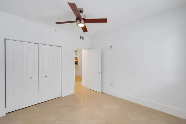 an empty room with a ceiling fan and window
