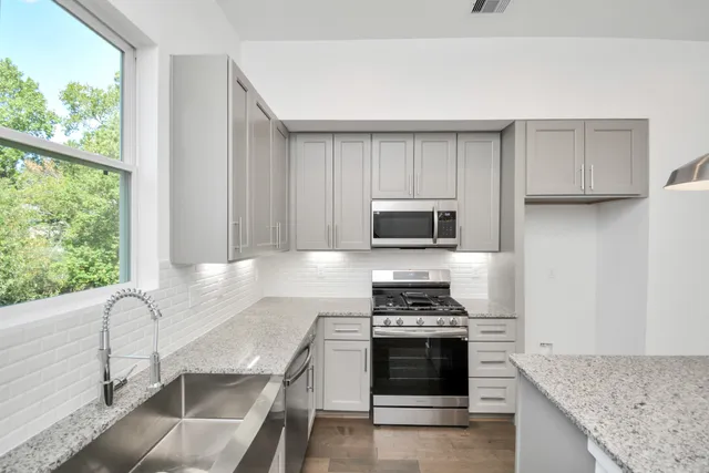 a kitchen with stainless steel appliances granite countertop a stove a sink and a microwave