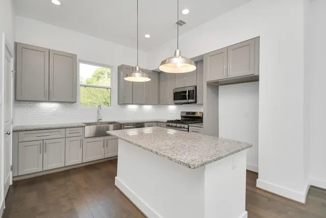 a kitchen with kitchen island granite countertop a stove a sink a center island and cabinets