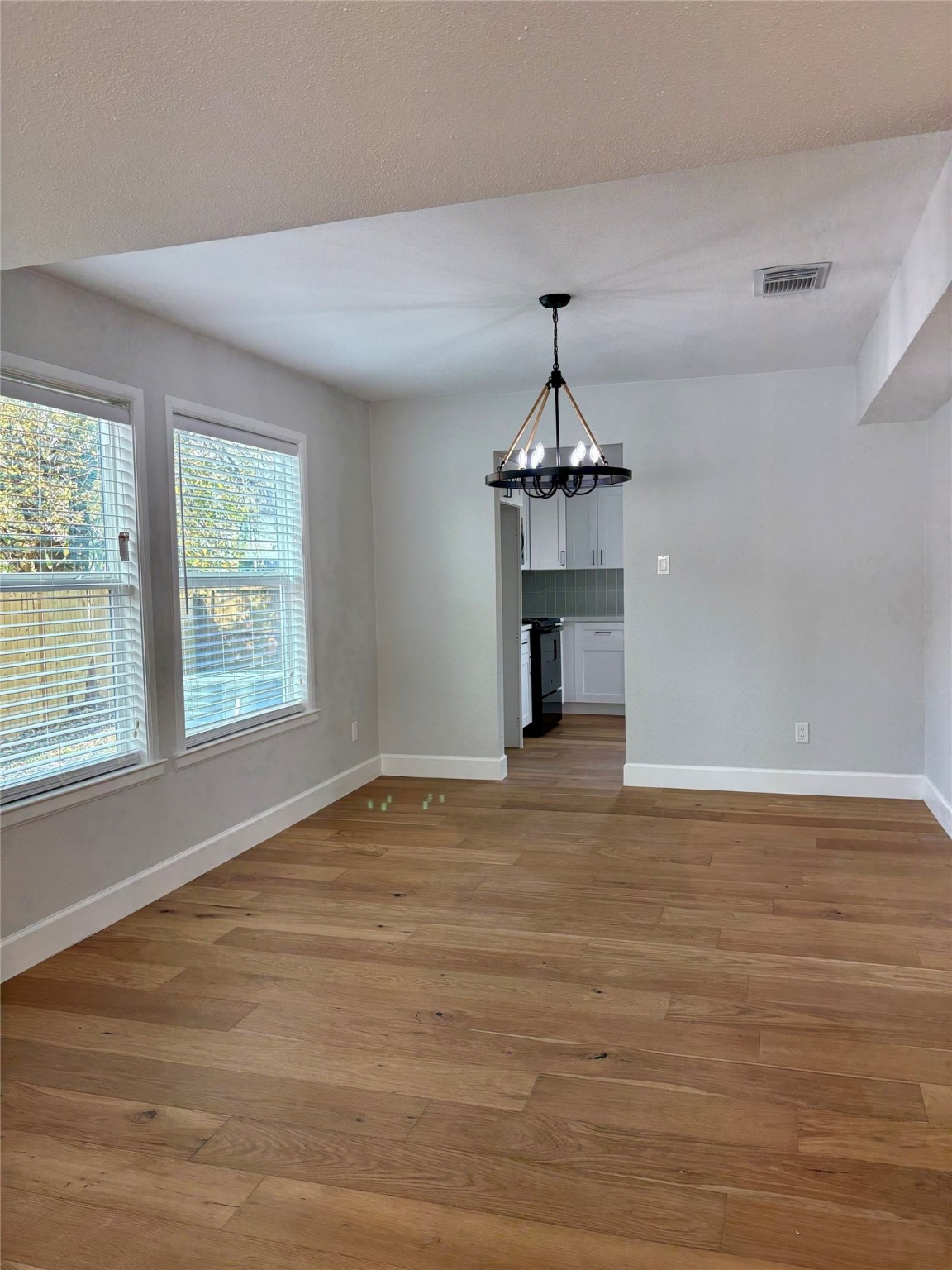 12303 Split Rail Lane Houston, TX 77071 - Photo 20 of 50 The dining room exudes modern elegance with fresh paint, new texture, and warm engineered white oak flooring, beautifully complemented by a stylish modern chandelier that adds a perfect touch of sophistication and charm.
