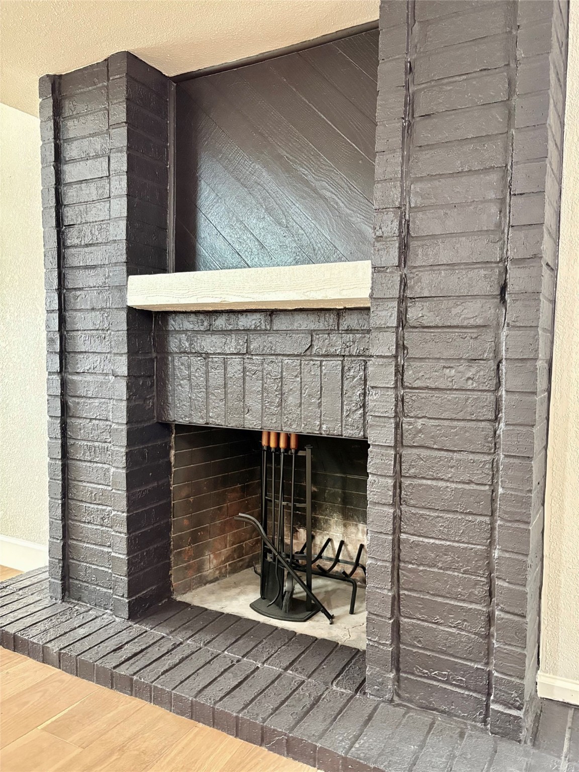 12303 Split Rail Lane Houston, TX 77071 - Photo 23 of 50 The classic wood-burning brick fireplace, freshly painted in a rich black finish, adds timeless character and modern contrast — the perfect blend of warmth, style, and craftsmanship.