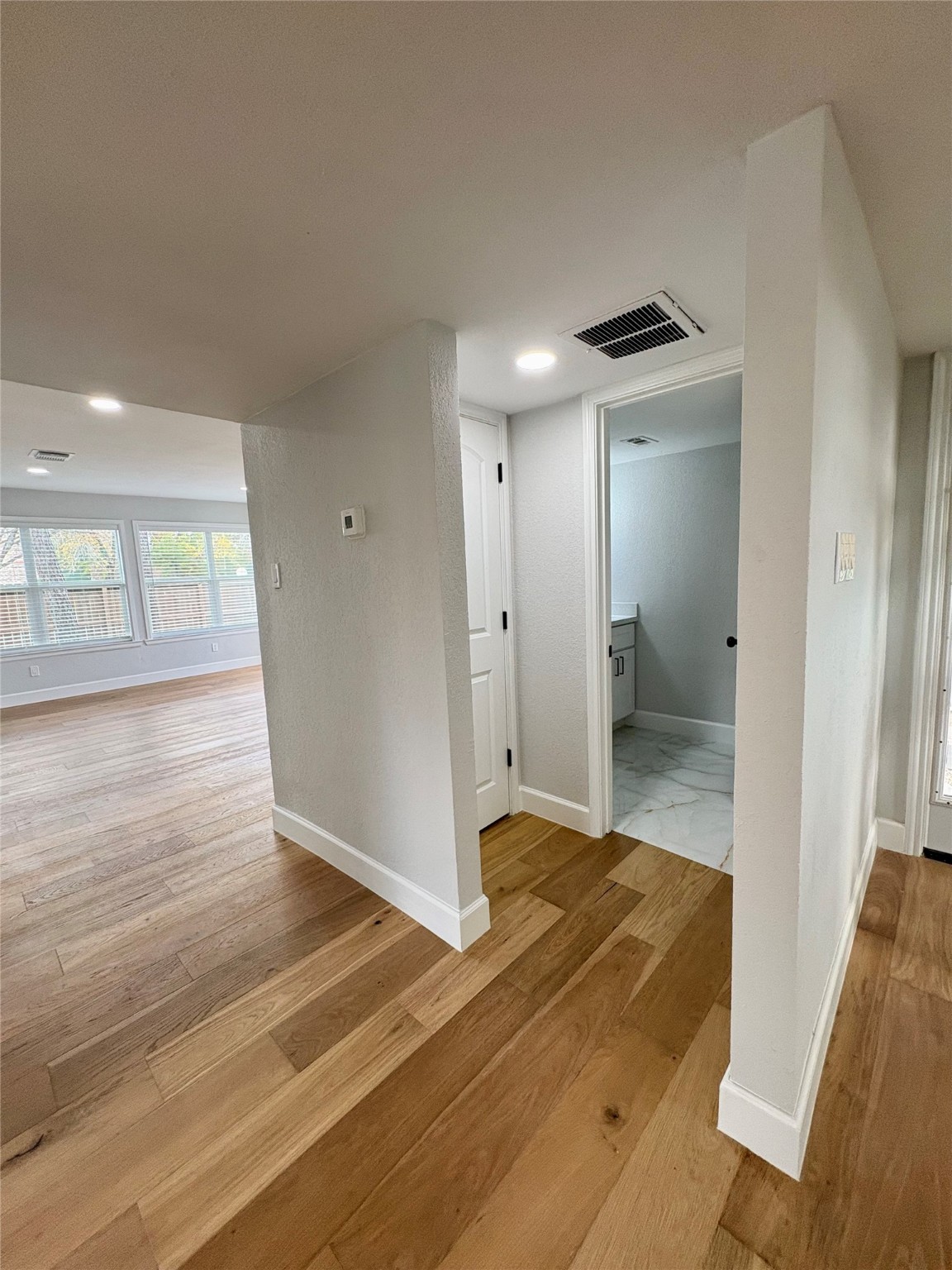 12303 Split Rail Lane Houston, TX 77071 - Photo 24 of 50 This view from the entry showcases the beautifully installed 5½-inch baseboards that frame the new white oak flooring throughout the hall, breakfast area, and half bath—adding a refined finishing touch to the home’s modern, cohesive design.