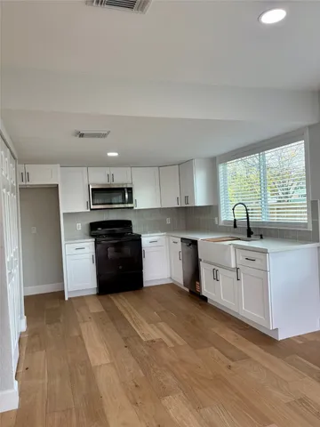 a kitchen with granite countertop a stove top oven sink and cabinets