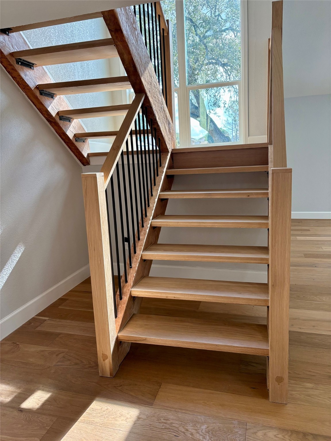 12303 Split Rail Lane Houston, TX 77071 - Photo 34 of 50 From the lower level, the view highlights the beautiful craftsmanship of the cedar and white oak staircase complemented by a large newly installed window that fills the space with natural light and a serene view of the exterior.