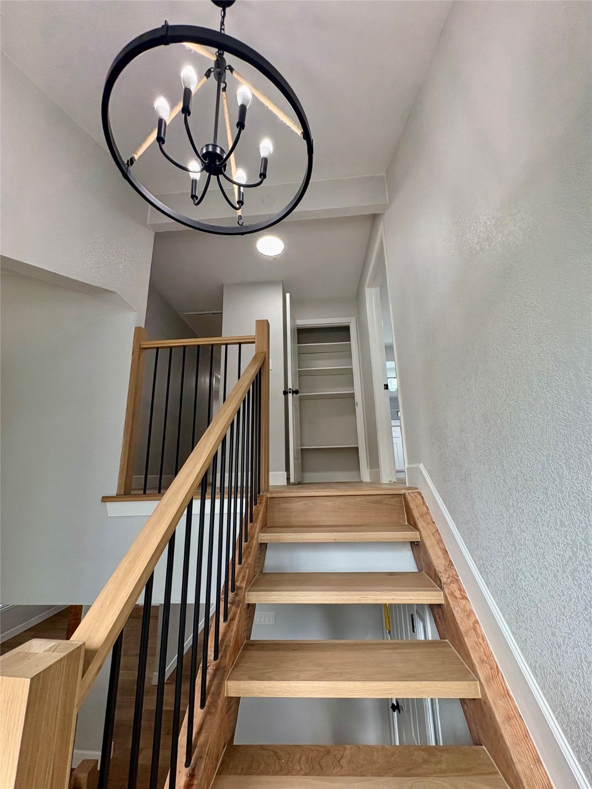12303 Split Rail Lane Houston, TX 77071 - Photo 35 of 50 A mid-level perspective showcases the elegant transition to the second floor and the modern chandelier, enhancing the open design and warm, contemporary feel of the home.