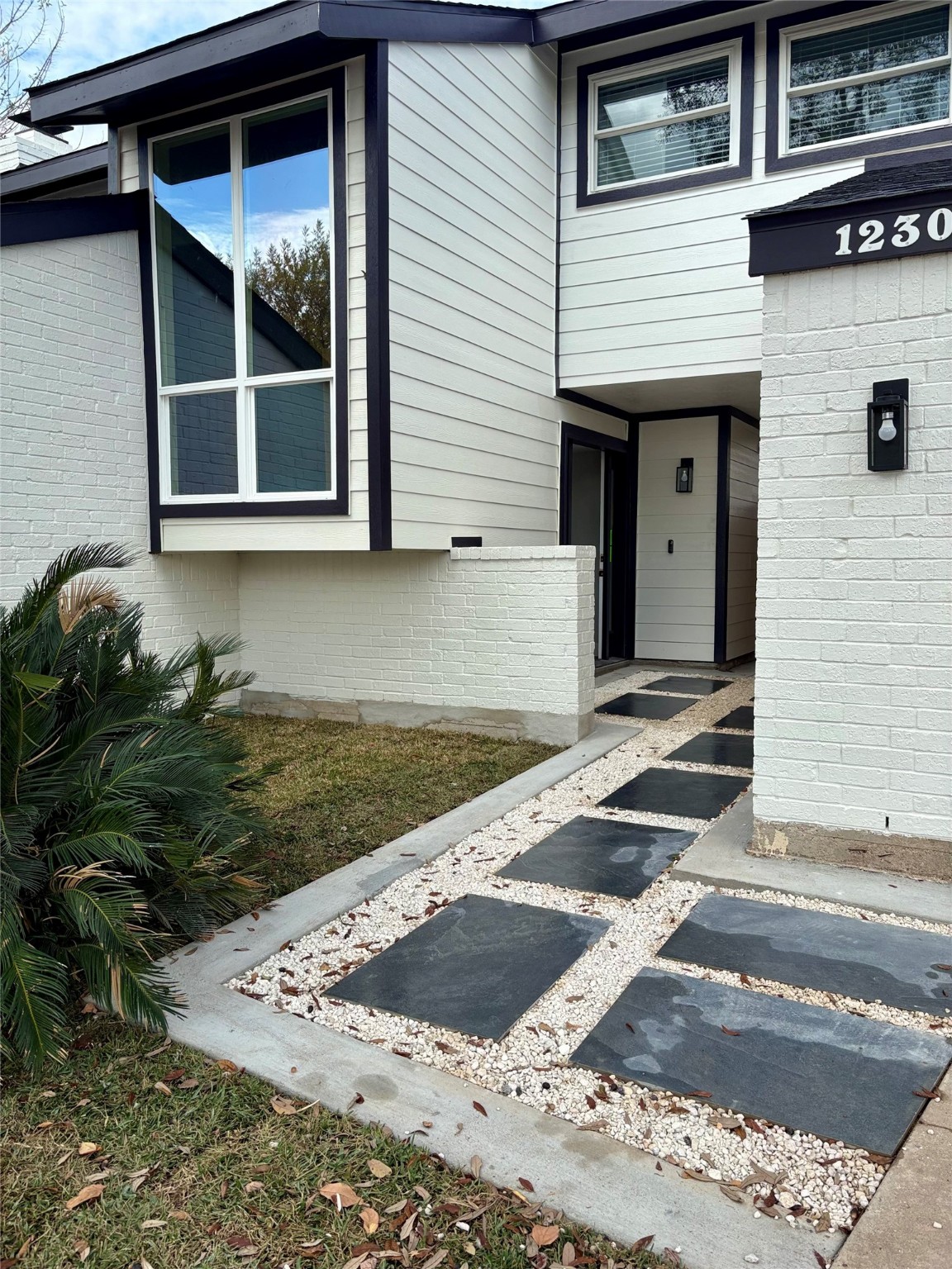 12303 Split Rail Lane Houston, TX 77071 - Photo 4 of 50 The redesigned entry pathway combines gravel, pavers, and concrete, creating a welcoming and contemporary approach to the front entrance.