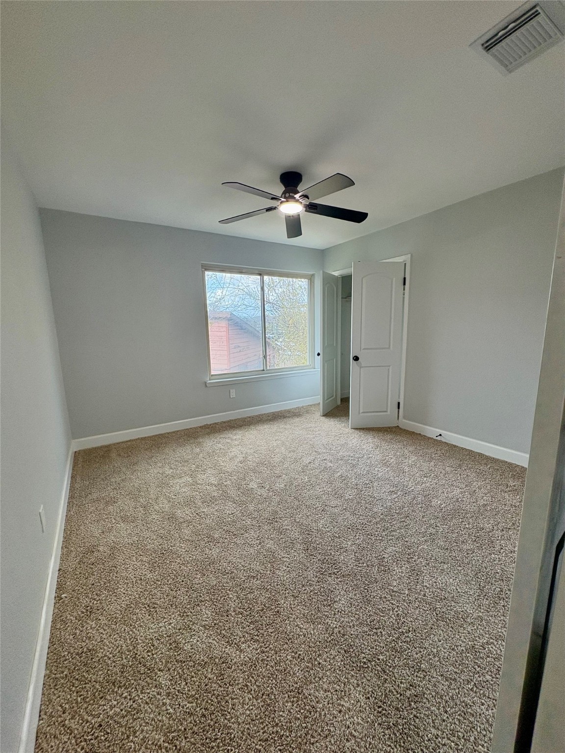 12303 Split Rail Lane Houston, TX 77071 - Photo 42 of 50 The second bedroom offers a comfortable and inviting atmosphere with new carpet flooring, fresh paint and texture, a modern ceiling fan, and a new Roman-style door, creating a clean and relaxing space filled with natural light.