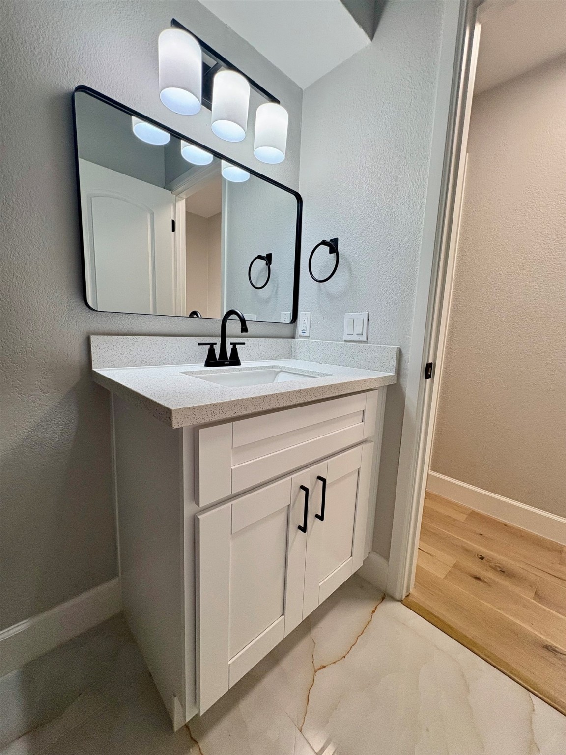 12303 Split Rail Lane Houston, TX 77071 - Photo 46 of 50 The vanity area includes a white quartz countertop, new cabinet with black hardware, a matte-black faucet, and a modern light fixture, blending style and functionality for a refined finish.