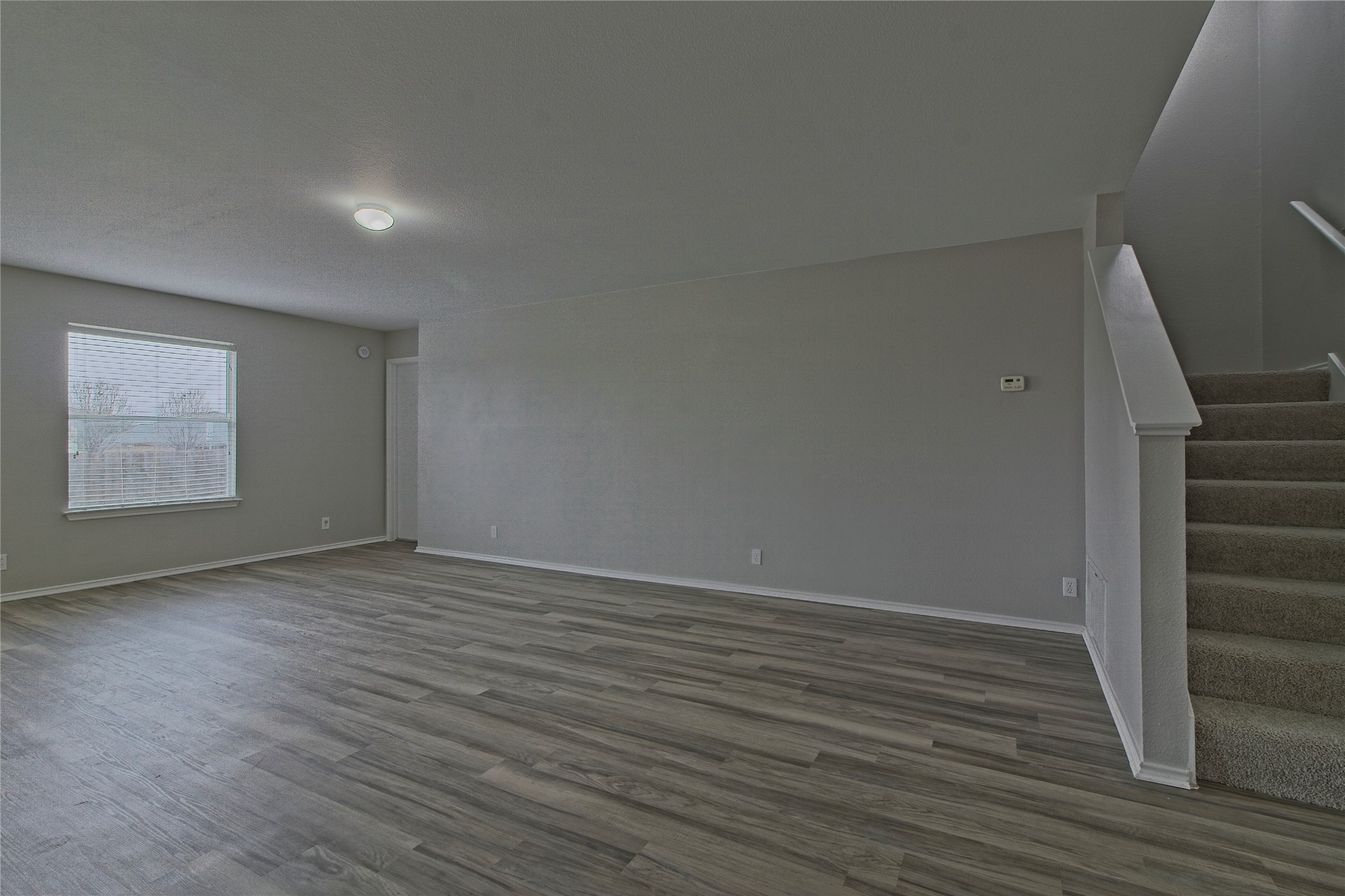 232 Brickyard Lane Jarrell, TX 76537 - Photo 9 of 31 A well-lit interior features wide plank flooring and a carpeted staircase.