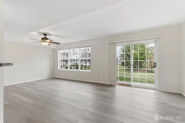 an empty room with wooden floor cabinet and windows