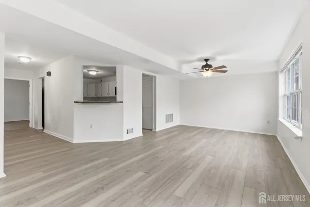 a view of empty room with wooden floor and window