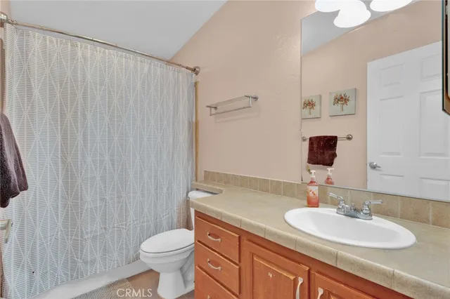 a bathroom with a granite countertop sink a toilet and a mirror