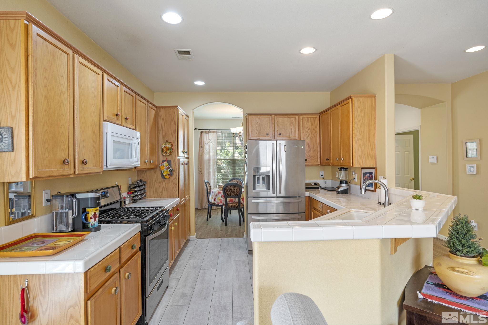 10465 Summershade Lane Reno, NV 89521 - Photo 11 of 30 a kitchen with sink refrigerator dining table and chairs