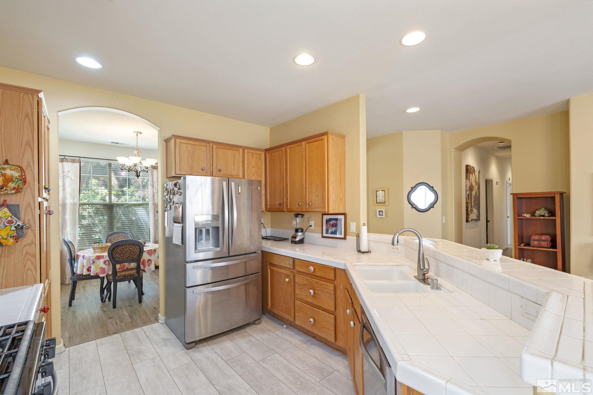 10465 Summershade Lane Reno, NV 89521 - Photo 15 of 30 a kitchen with stainless steel appliances kitchen island granite countertop a refrigerator a stove a sink dishwasher a dining table and chairs with wooden floor
