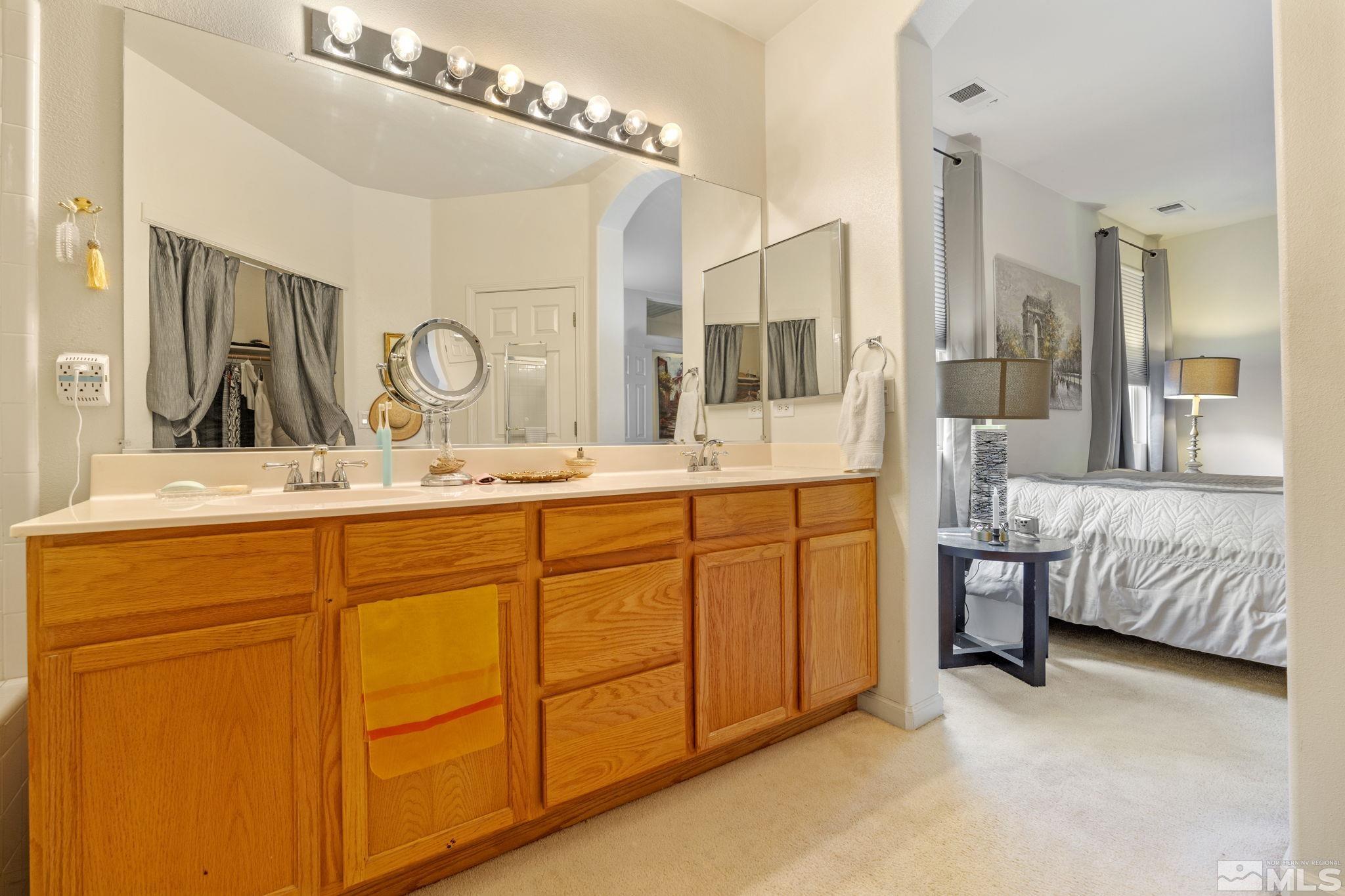10465 Summershade Lane Reno, NV 89521 - Photo 24 of 30 a bathroom with a double vanity sink a mirror and a bathtub