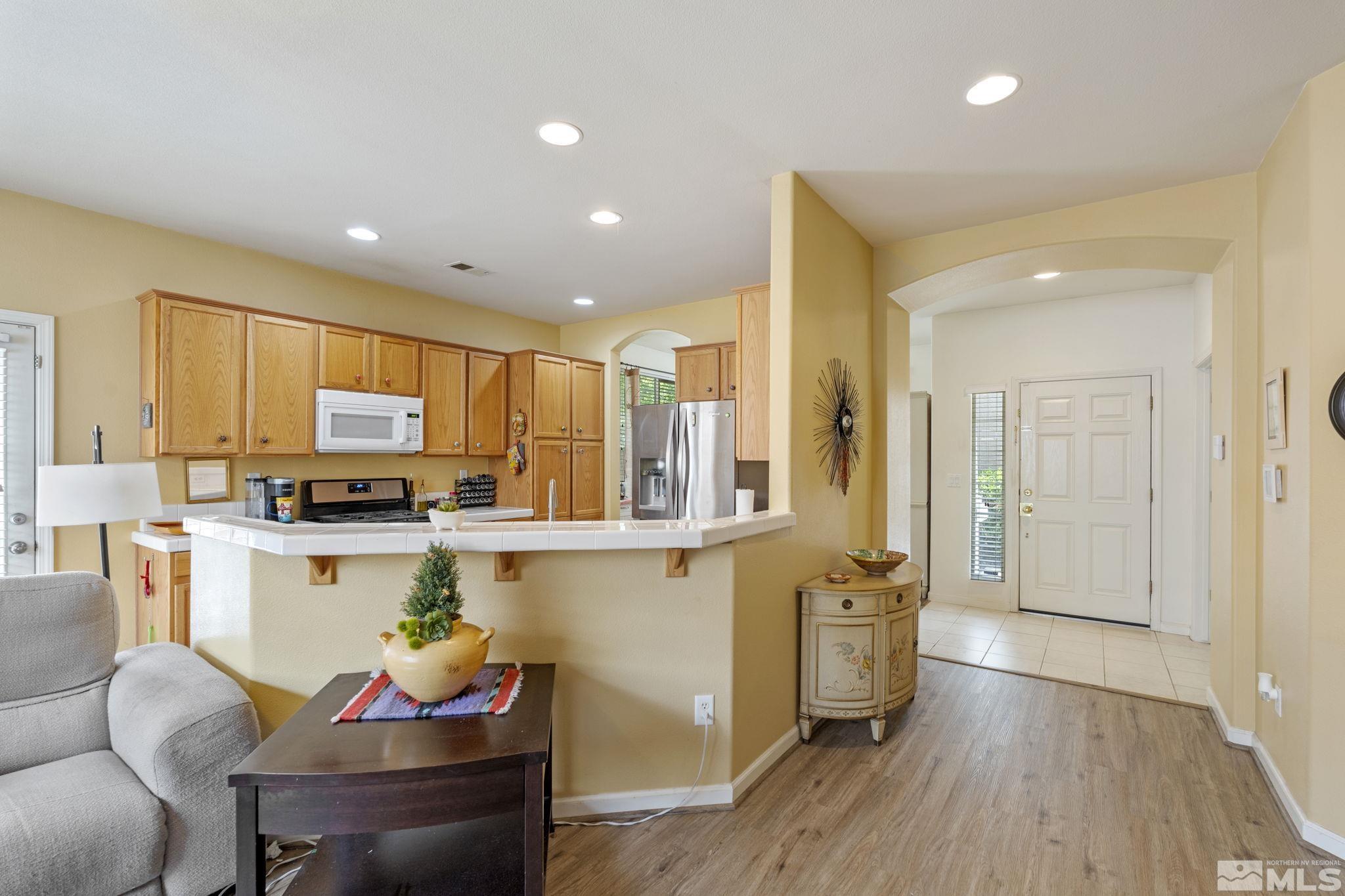 10465 Summershade Lane Reno, NV 89521 - Photo 5 of 30 a kitchen with stainless steel appliances granite countertop a refrigerator a sink dishwasher a dining table and chairs with wooden floor