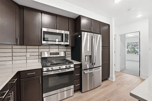 a kitchen with granite countertop a refrigerator and a stove top oven