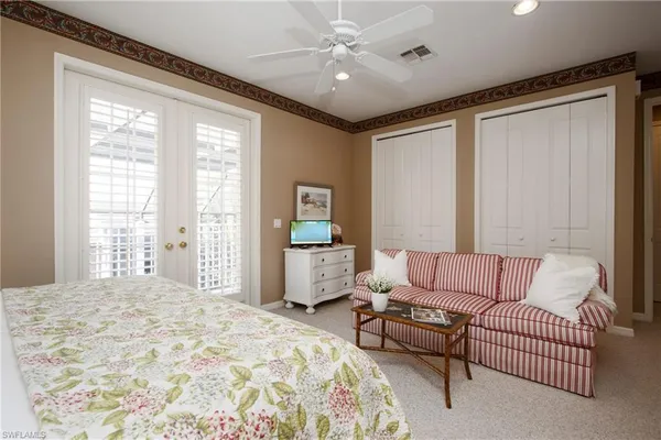 a spacious bedroom with a bed couch and windows