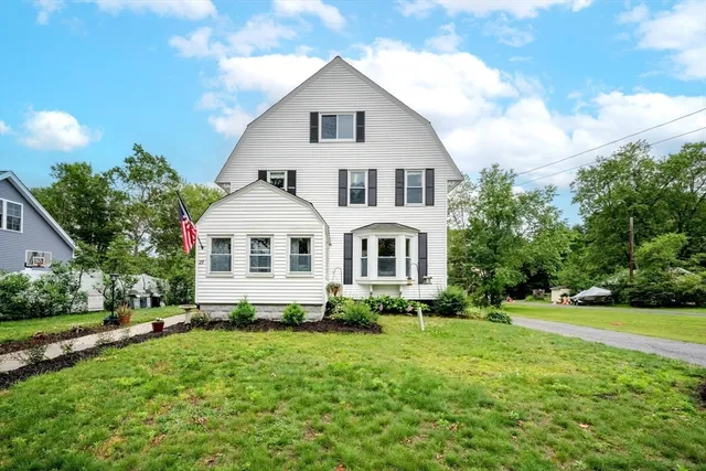a white house with a small yard and trees