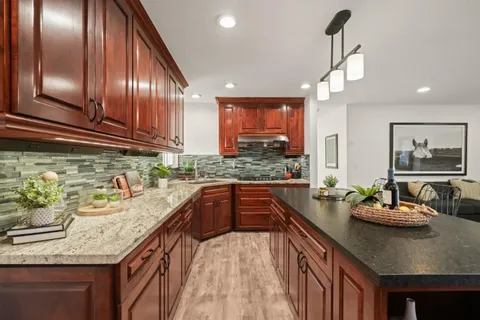 a kitchen with stainless steel appliances granite countertop a sink a stove and a wooden floor