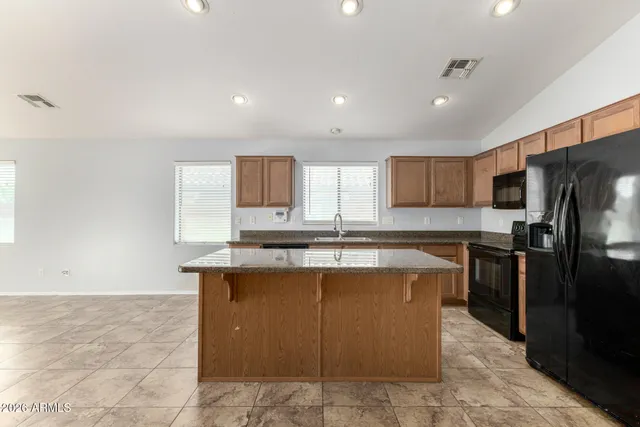 a kitchen with kitchen island a counter top space a sink stainless steel appliances and cabinets