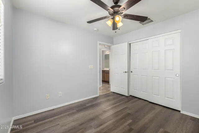 an empty room with wooden floor fan and windows
