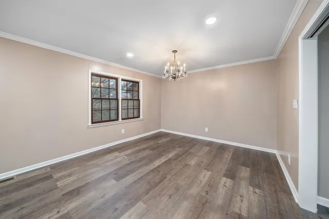 a view of an empty room with wooden floor and windows