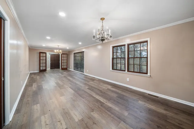 a view of a hallway with wooden floor and a chandelier