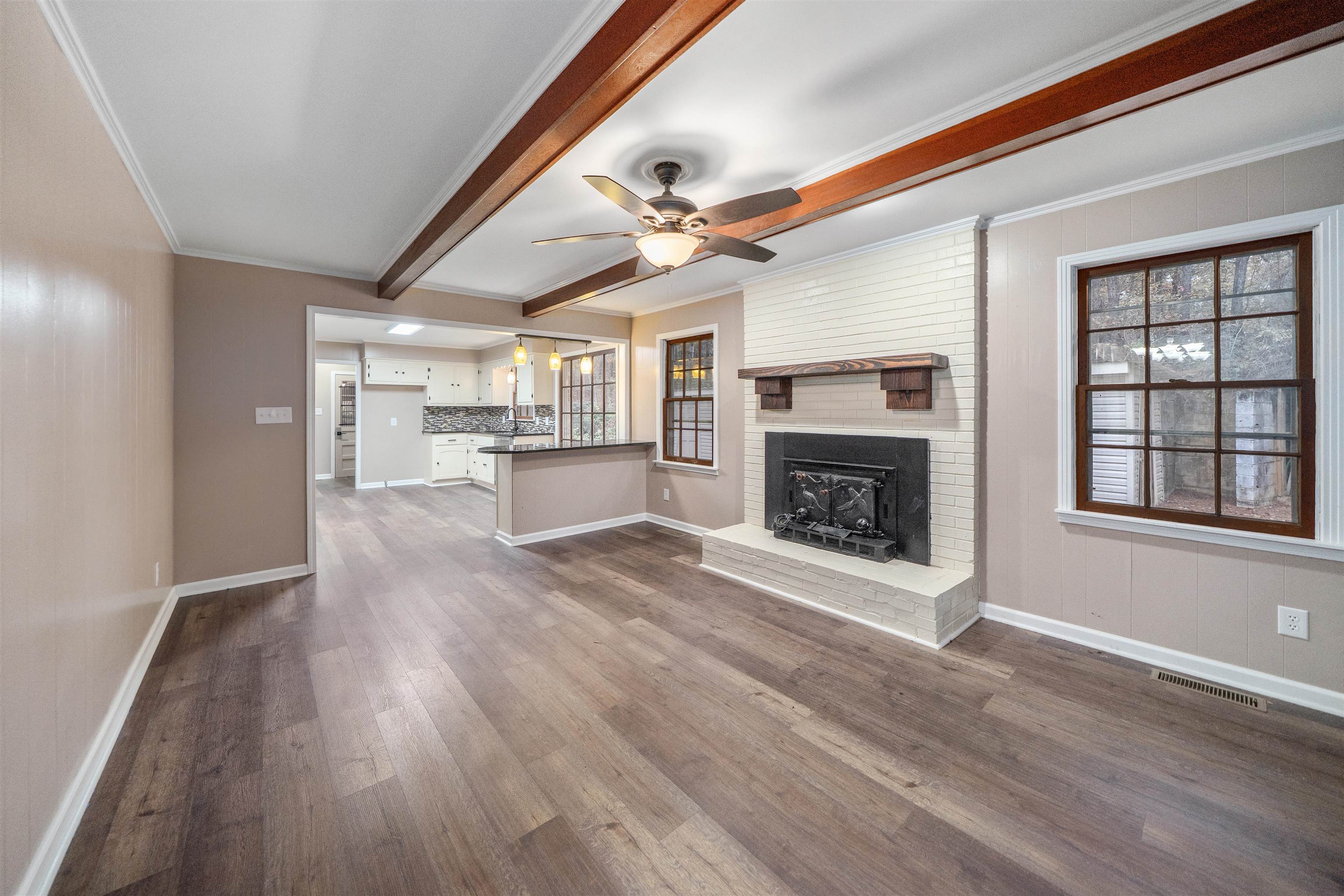 567 South 6th Street Selmer, TN 38375 - Photo 18 of 31 Unfurnished living room with beamed ceiling, dark wood-style floors, plenty of natural light, a fireplace, and crown molding