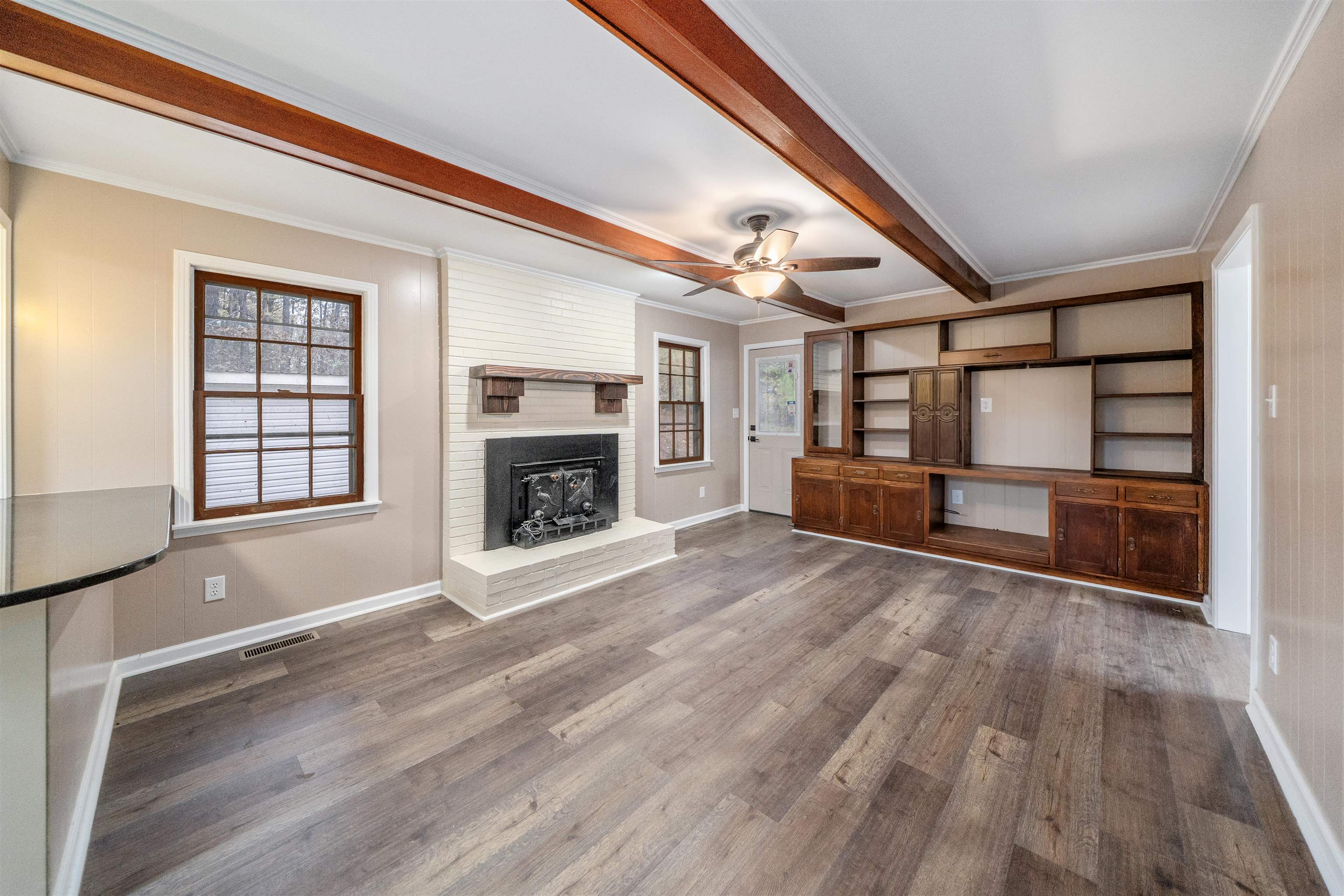 567 South 6th Street Selmer, TN 38375 - Photo 19 of 31 Unfurnished living room with beam ceiling, ceiling fan, dark wood-style flooring, ornamental molding, and a fireplace