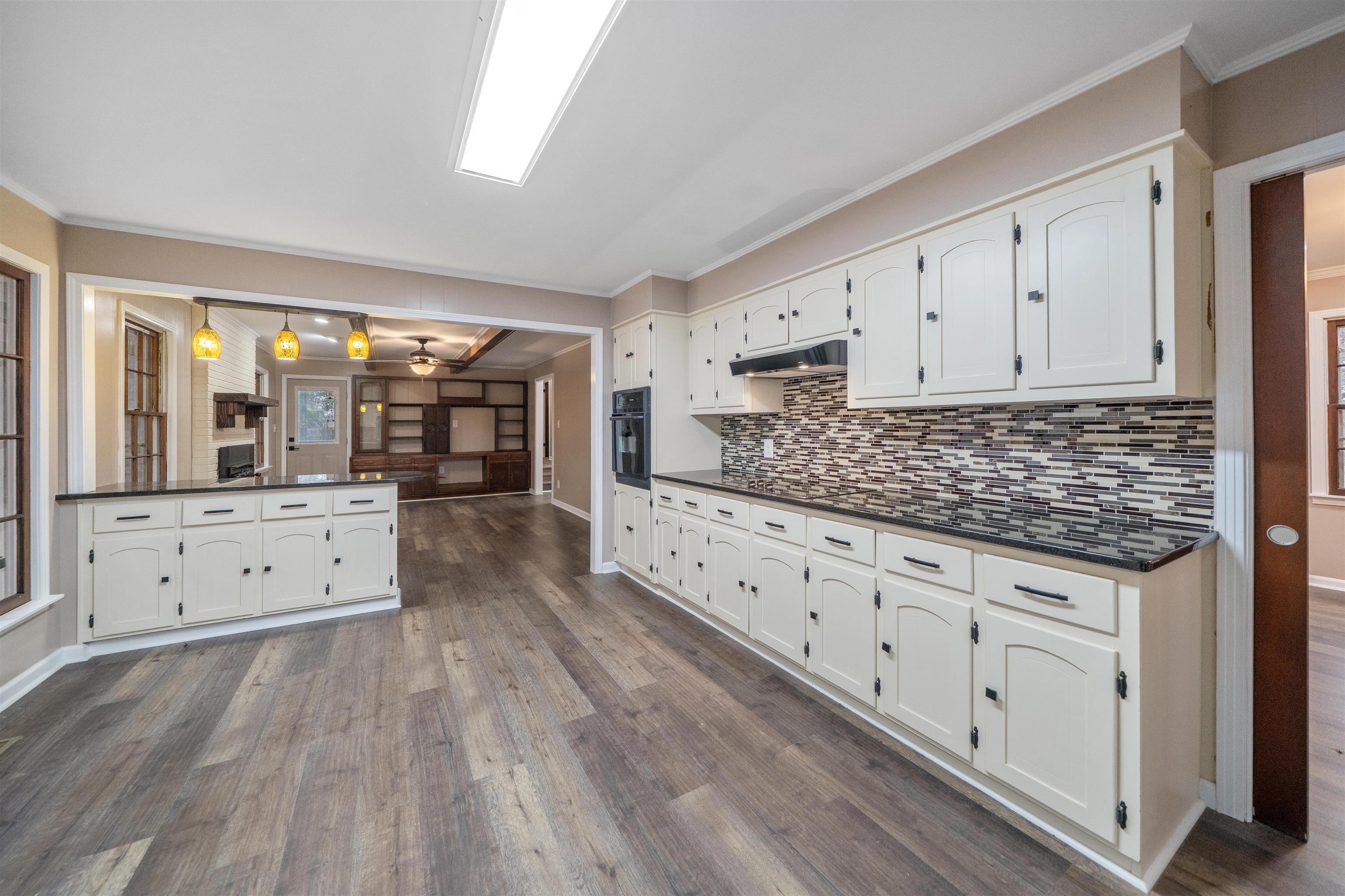 567 South 6th Street Selmer, TN 38375 - Photo 22 of 31 Kitchen featuring crown molding, hanging light fixtures, dark wood-style floors, white cabinets, and decorative backsplash