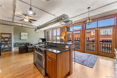 a kitchen with stainless steel appliances granite countertop a stove oven a sink dishwasher a dining table and chairs with wooden floor