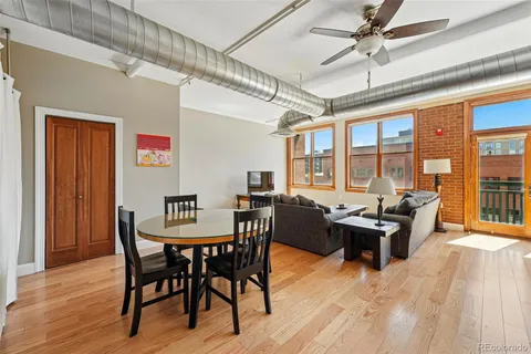 a dining room with wooden floor a chandelier fan a wooden table and chairs