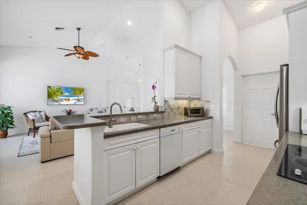 a kitchen with sink a refrigerator and white cabinets