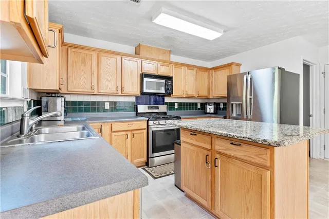 a kitchen with stainless steel appliances granite countertop a stove a sink and a microwave