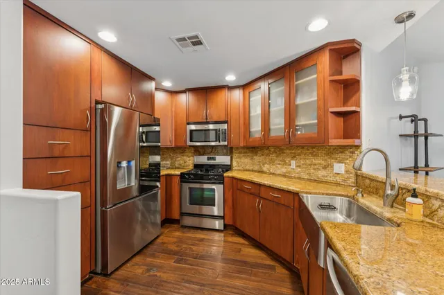 a kitchen with stainless steel appliances granite countertop refrigerator a stove top oven and sink