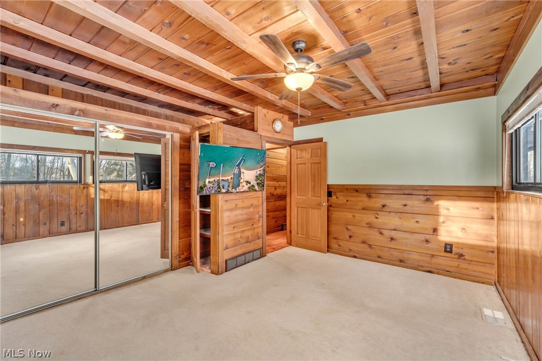 22791 Harms Road Euclid, OH 44143 - Photo 14 of 39 Unfurnished bedroom with wood walls, a wood ceiling with exposed beams, carpet, ceiling fan, and a wainscoted wall