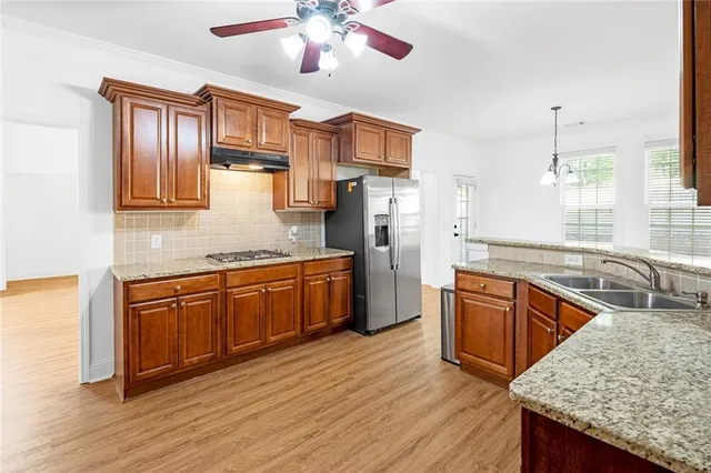 a kitchen with stainless steel appliances granite countertop hardwood floor sink stove dining table and chairs