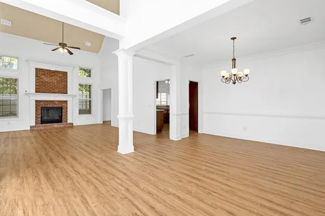 a view of an empty room with wooden floor fireplace and a window