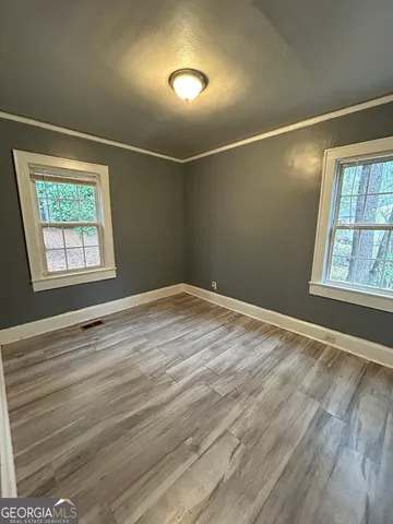 a view of an empty room with a window and wooden floor