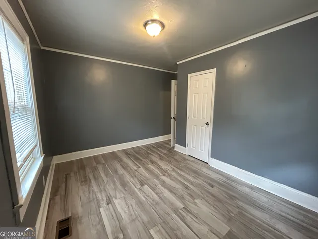 an empty room with wooden floor and windows