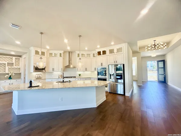 an empty room with wooden floor and a kitchen view