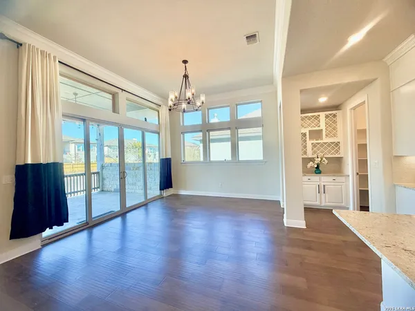 a view of an empty room with chandelier and wooden floor