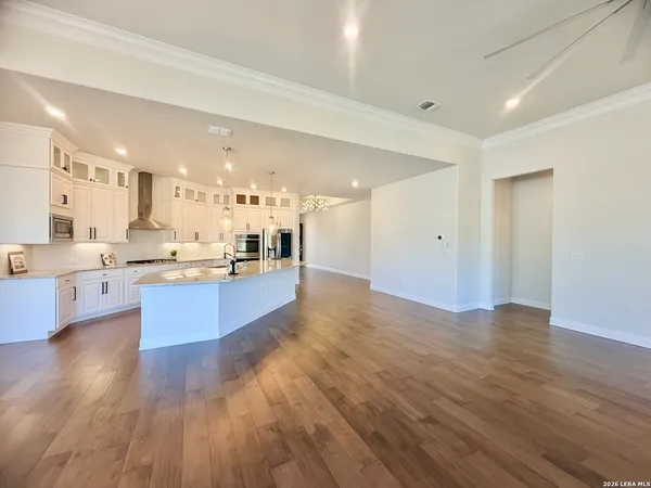a view of an empty room with kitchen and window
