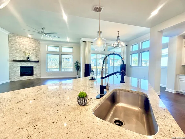a large kitchen with granite countertop lots of counter top space a sink stainless steel appliances and cabinets