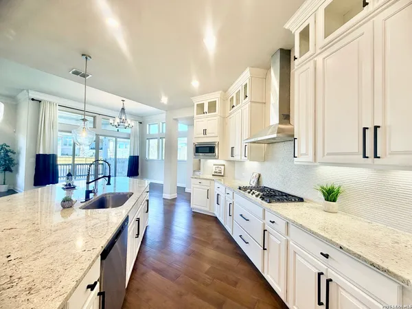 a large white kitchen with lots of counter top space a sink and stainless steel appliances