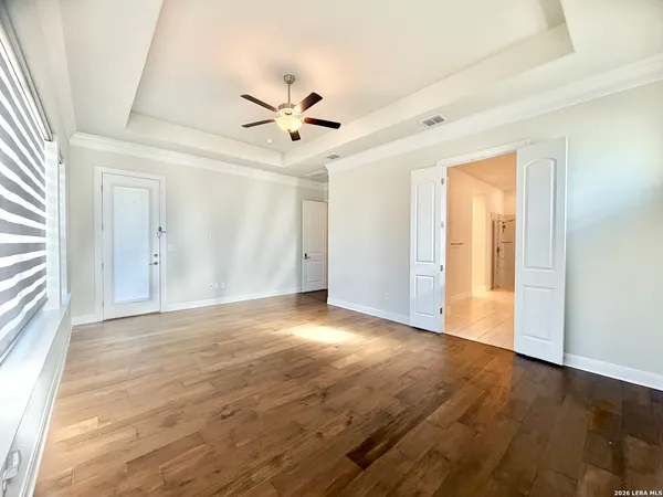 a view of an empty room with wooden floor and a window