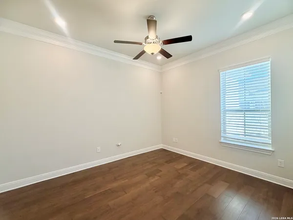 an empty room with wooden floor ceiling fan and windows