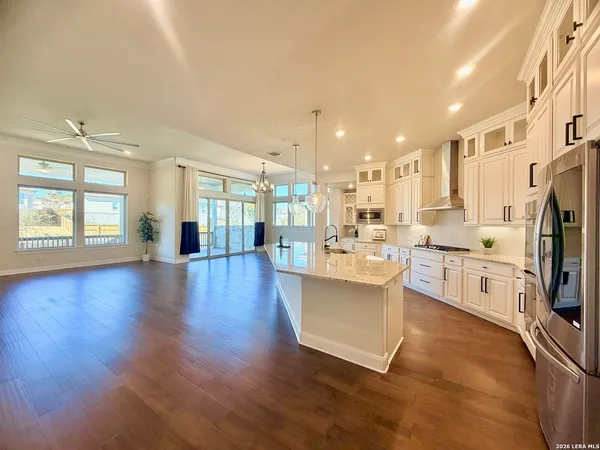 a living room with stainless steel appliances kitchen island granite countertop a stove a sink a refrigerator and cabinets